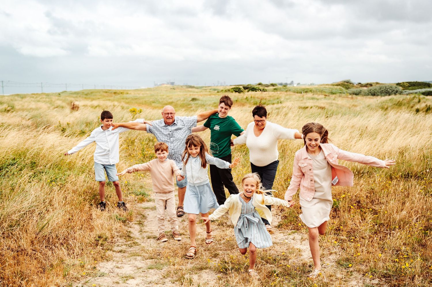 A group walking together through golden grass on a coastal path.
