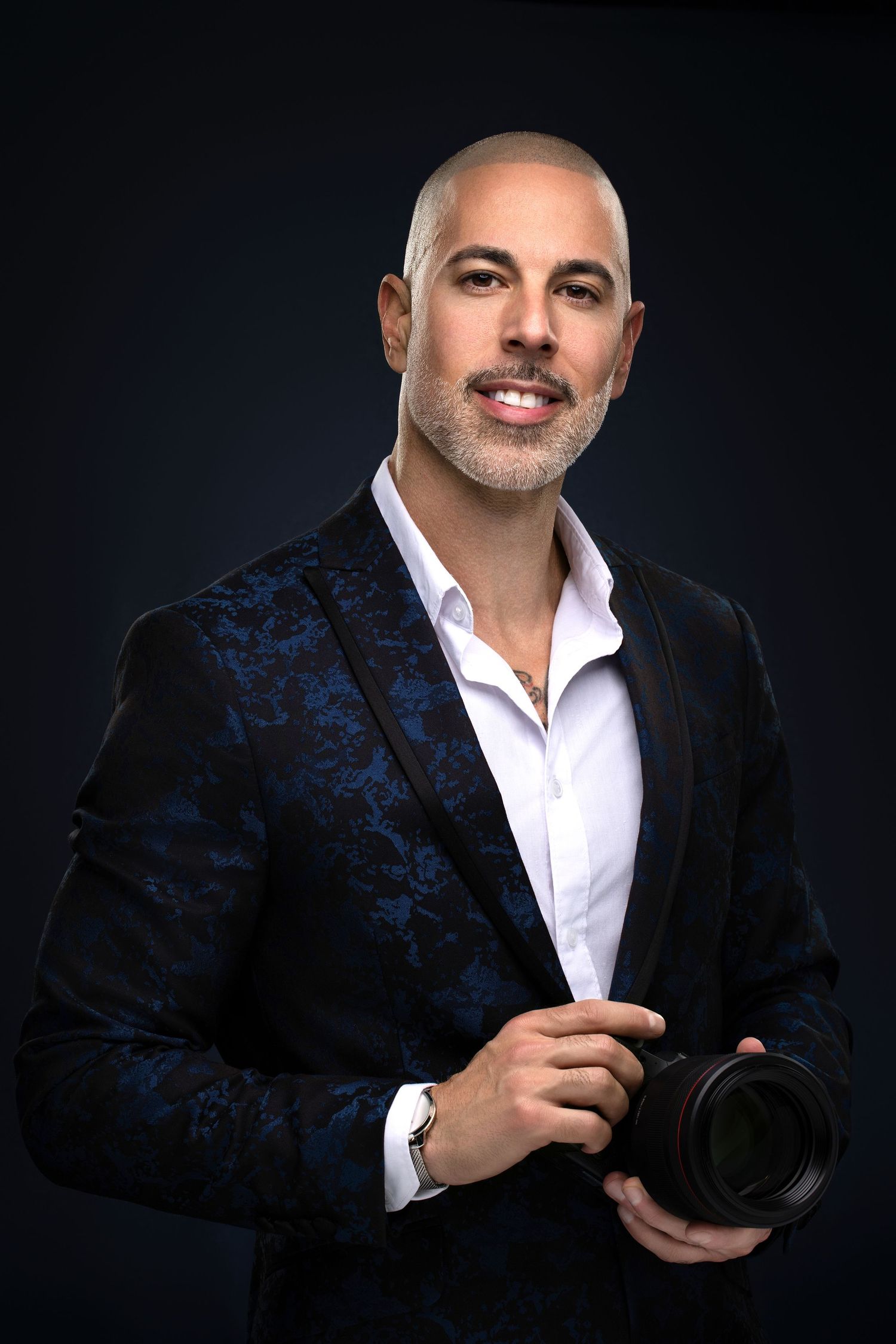 Professional studio portrait of a person wearing a white long-sleeve shirt against a light background.