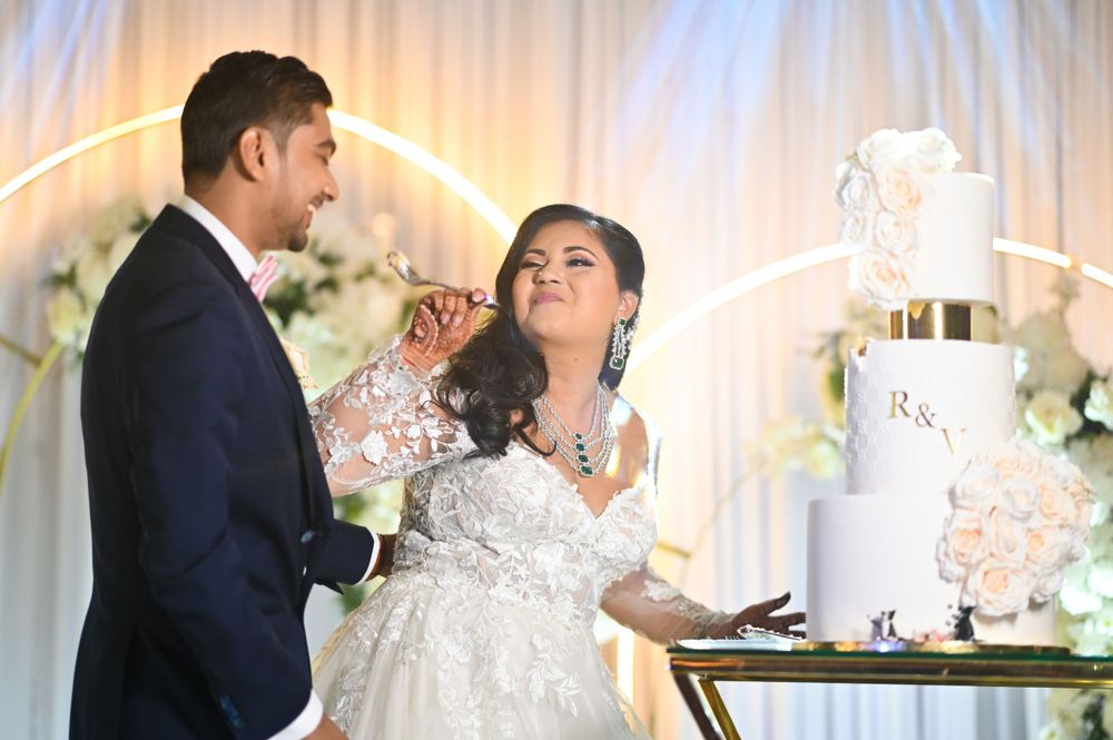 Couple shares playful moment while cutting their elegant white wedding cake.