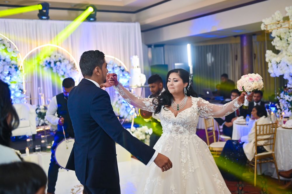 Couple dancing together at their wedding reception with decorative lighting and floral arrangements.