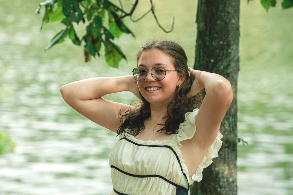 A summer portrait near a lake with trees and natural lighting.