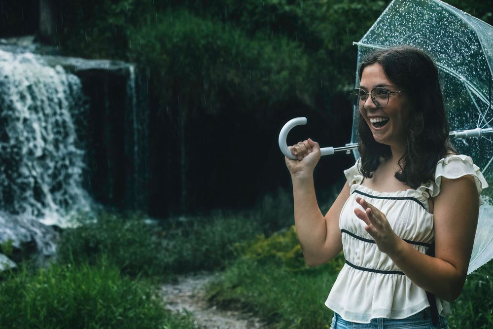 A joyful moment captured with a clear umbrella near a waterfall.