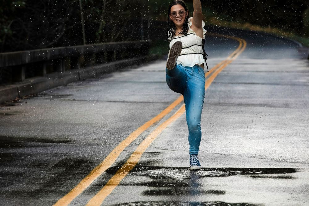 A graceful dance pose captured on a wet road with yellow line.