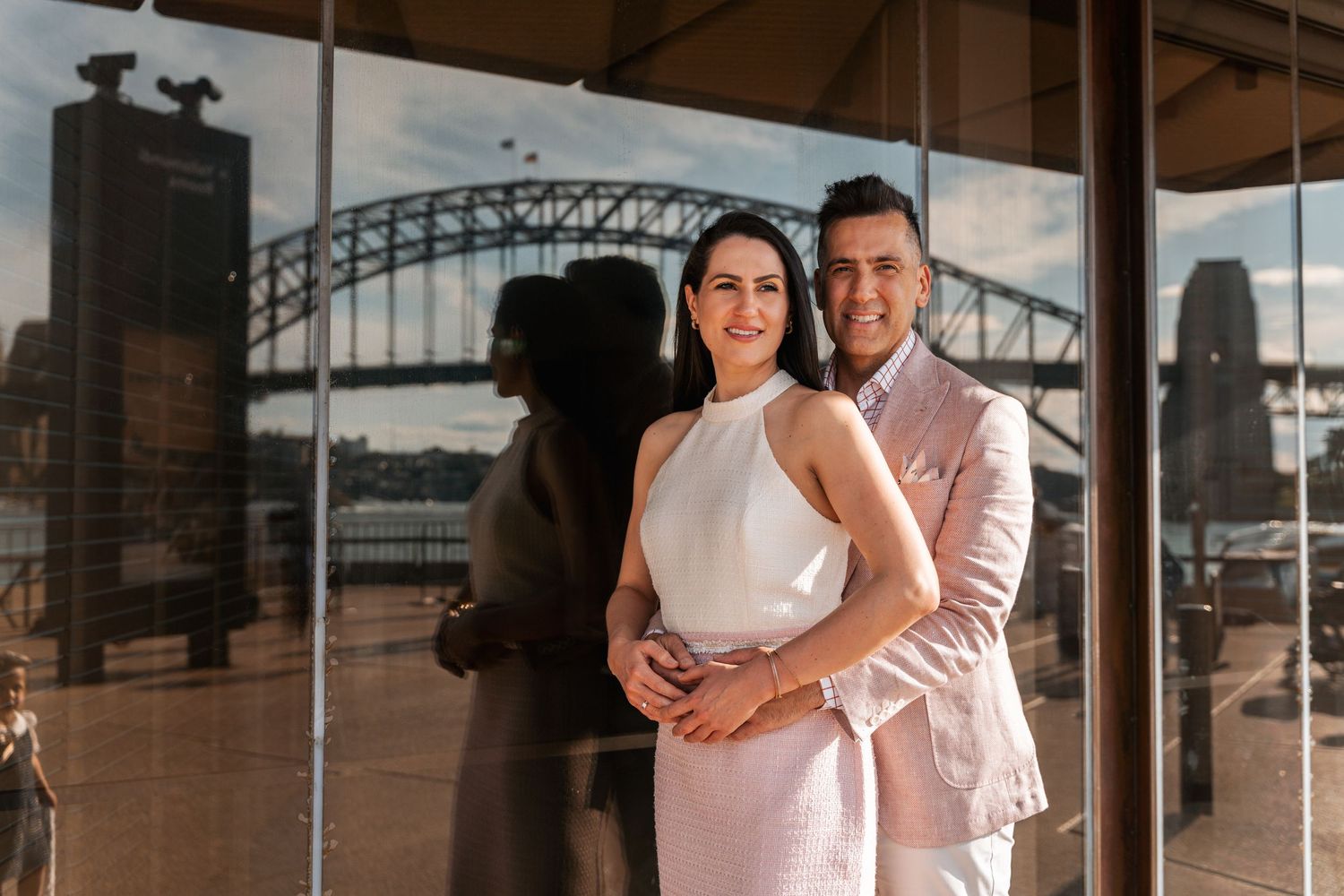 a couple hugging each other and in the background the Harbour Bridge is reflecting at a Sydney Photography Session