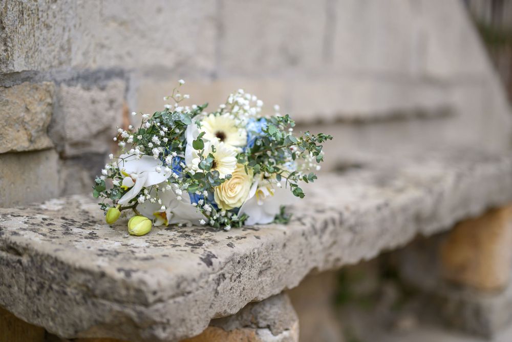 Delicate floral arrangements with white blooms and greenery displayed on stone surfaces.