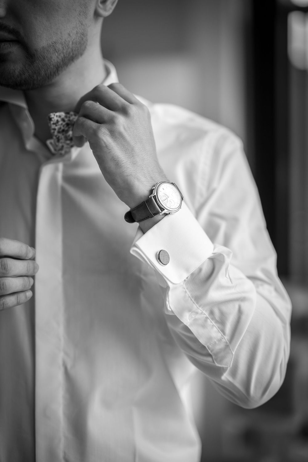 Black and white photo series showing someone adjusting the cuff of a crisp white dress shirt.