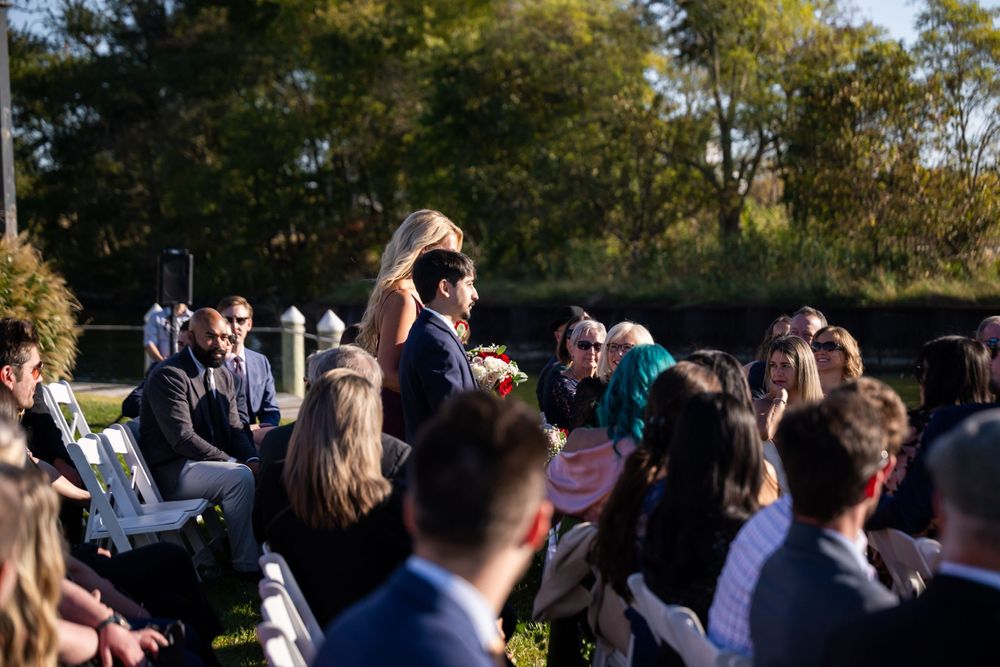 Wedding guests seated outdoors watching ceremony under blue autumn skies.