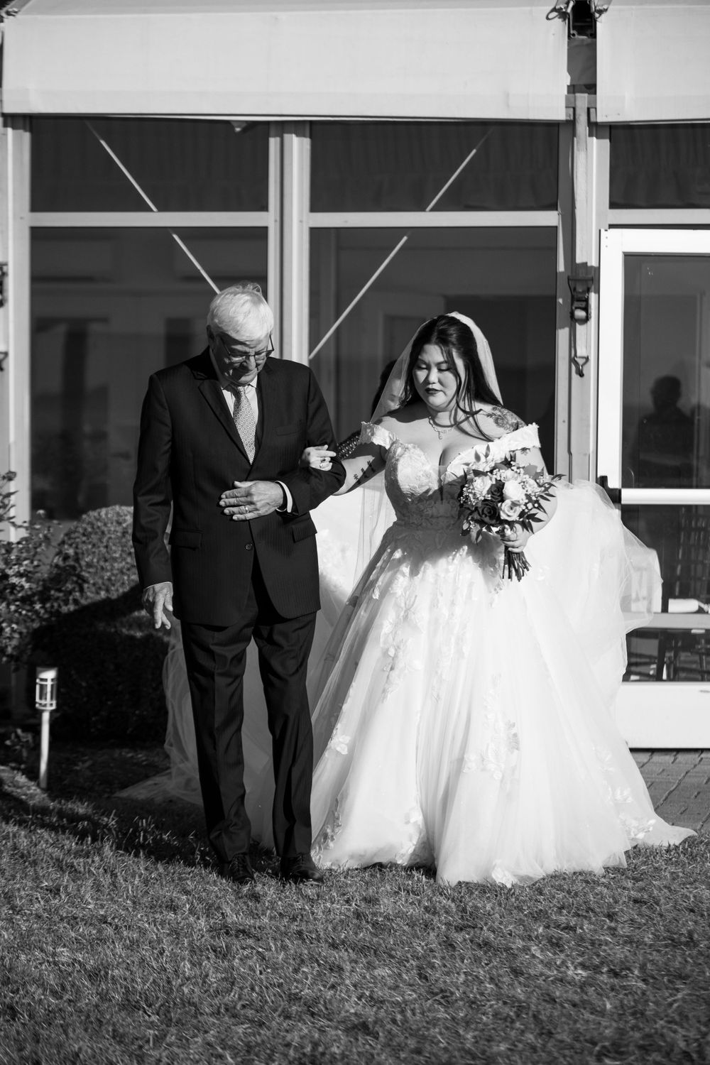 Black and white wedding photo sequence showing processional along building exterior.