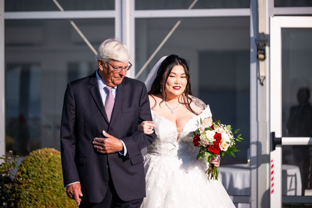 Wedding party poses outside modern building with white columns and glass windows.