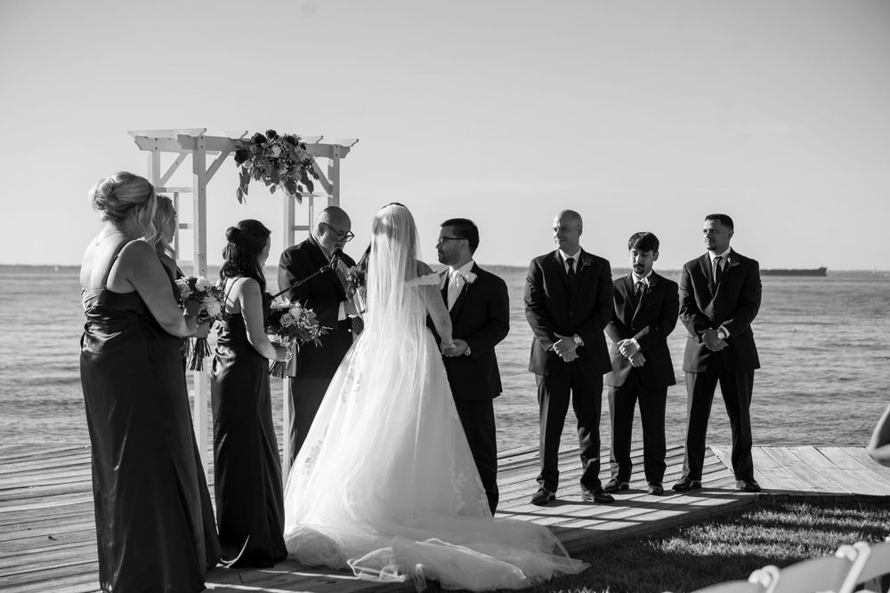 Oceanfront wedding ceremony with guests seated in rows facing decorated arch.