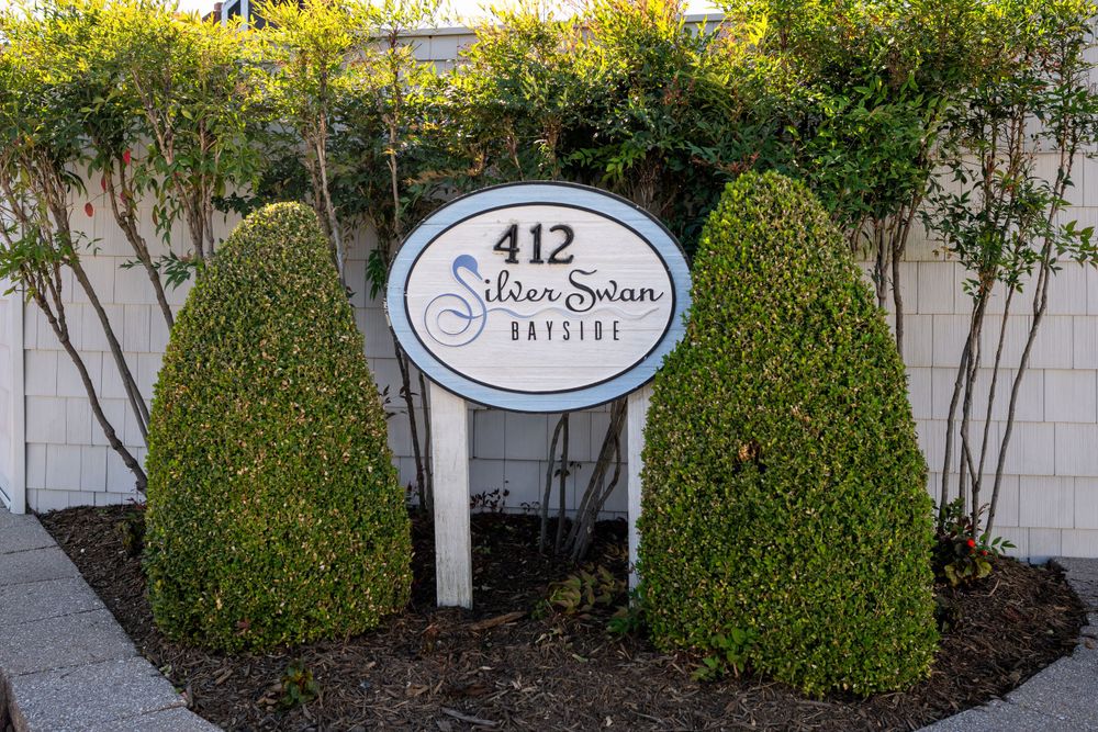 412 business sign flanked by manicured topiary bushes against white wall.