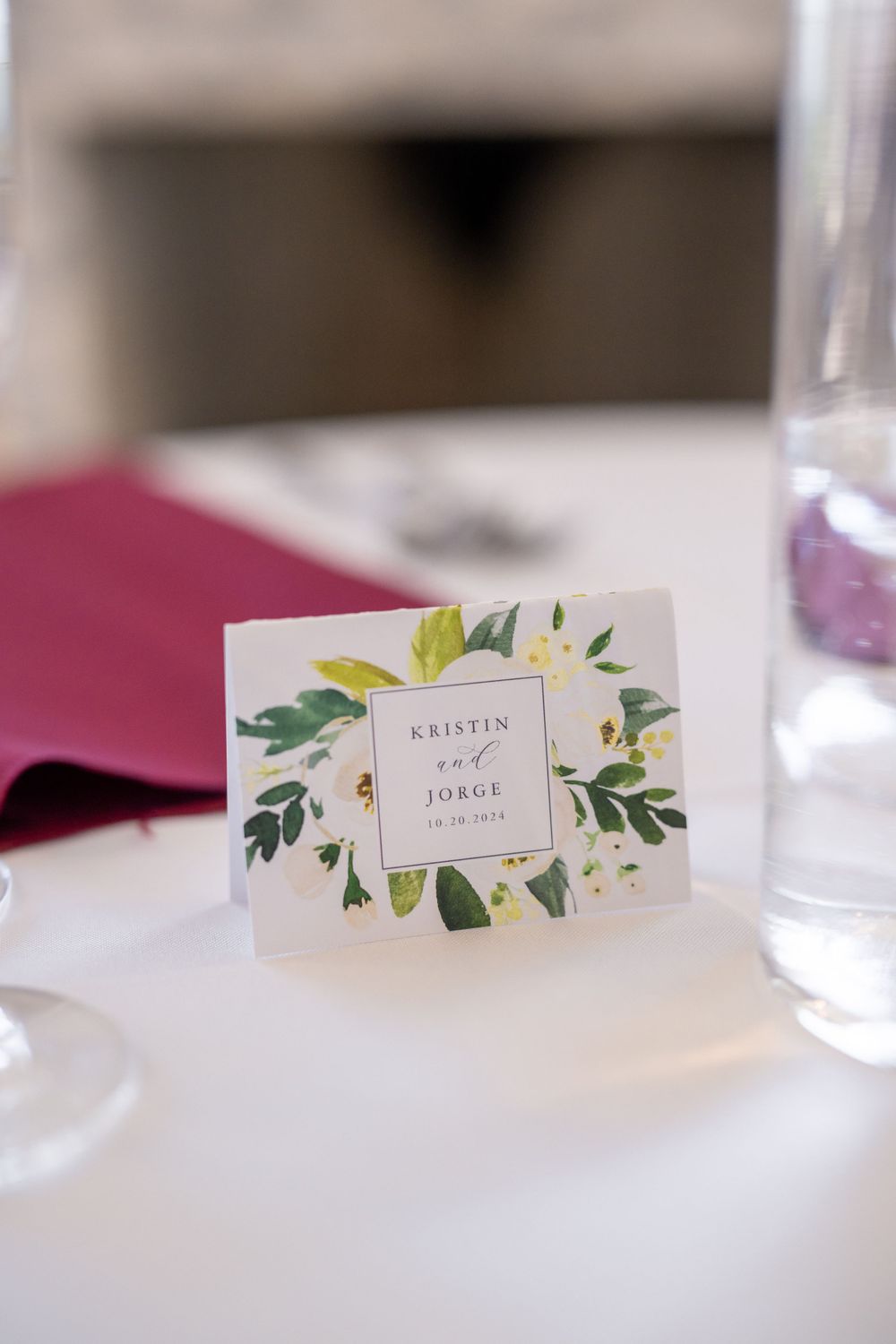 Elegant wedding place card with yellow and green floral design border on white table setting.