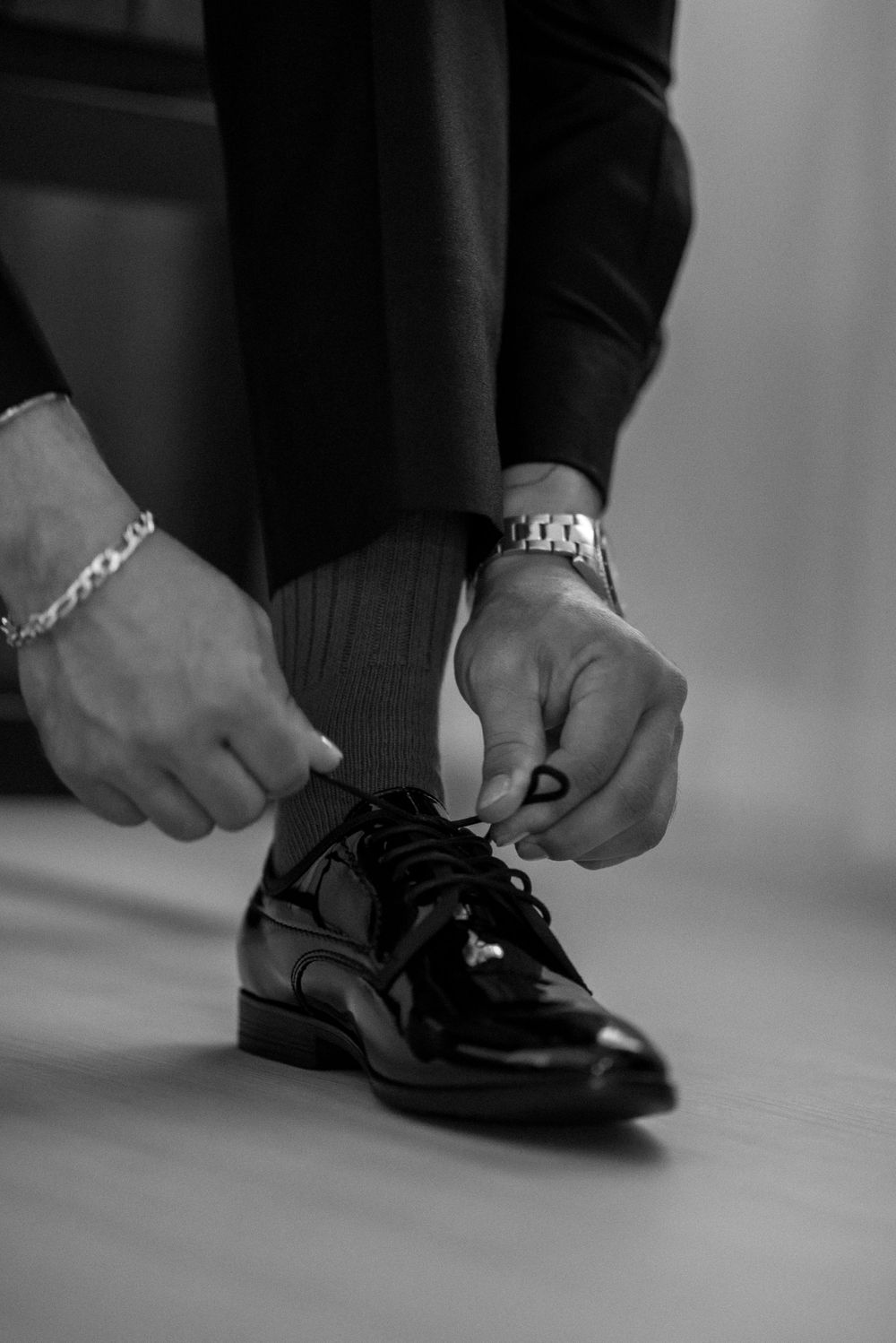 Close-up of hands tying shiny black formal dress shoes.