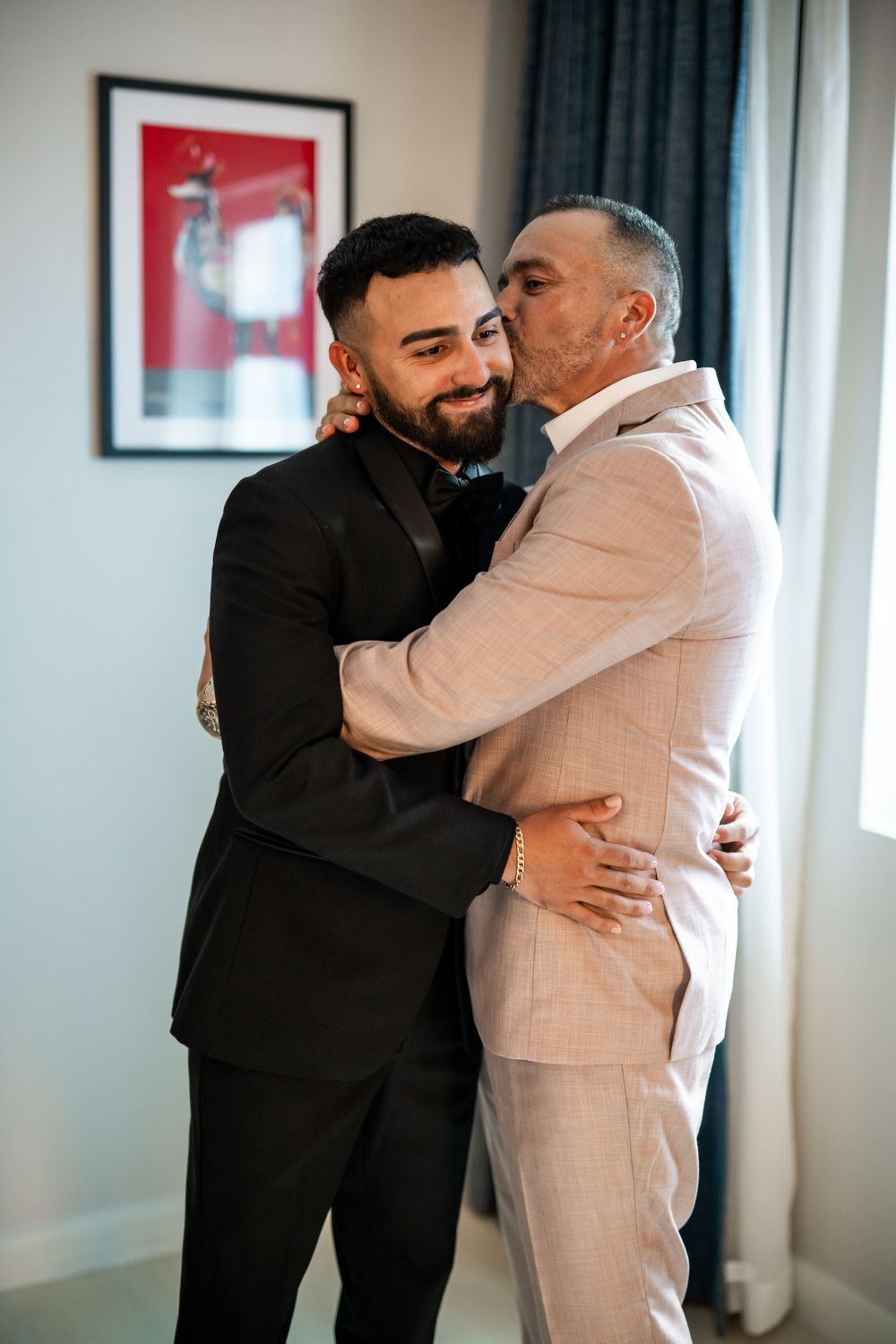Emotional moments of wedding day embrace between people in black and cream formal attire.