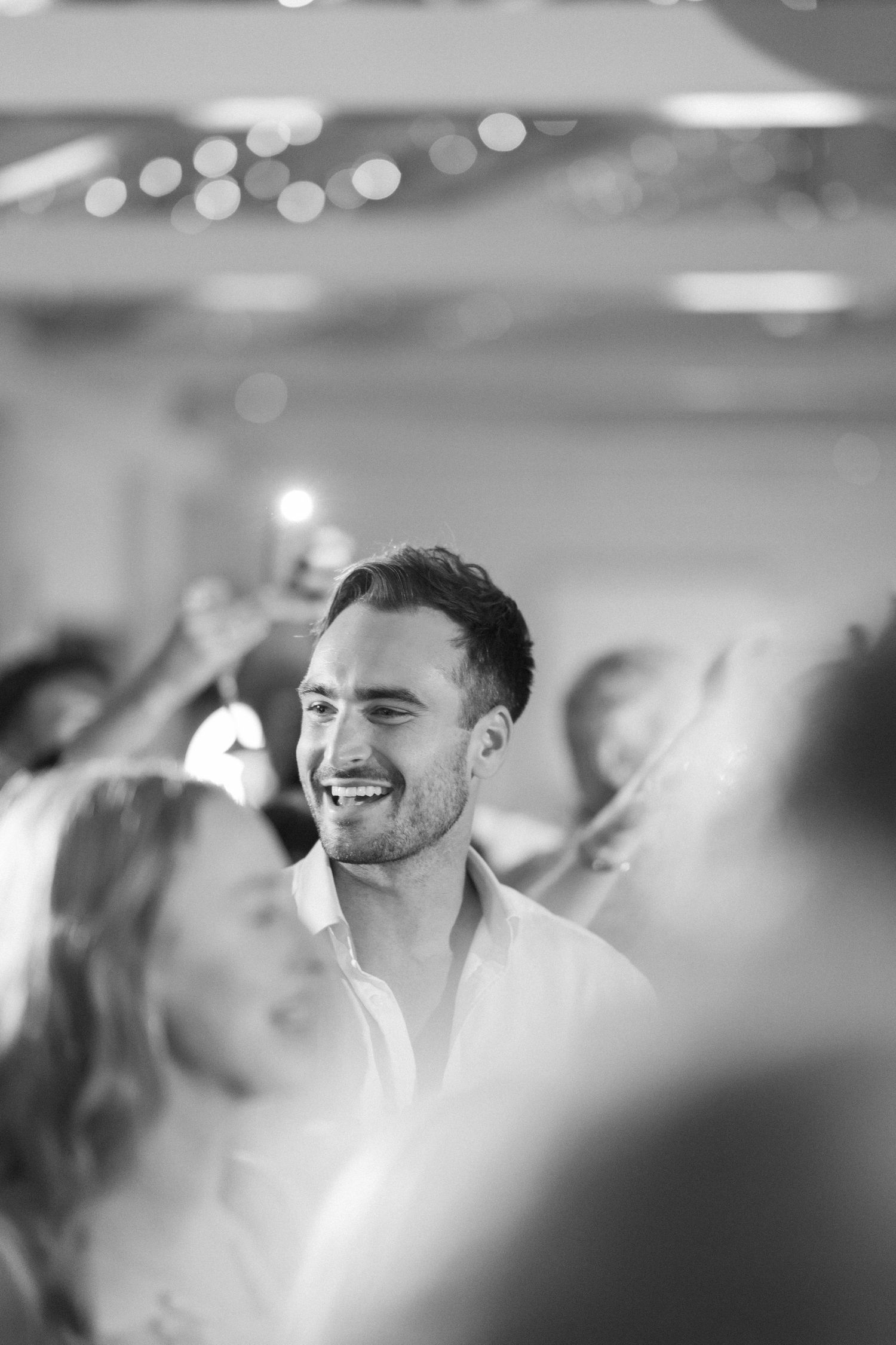 Black and white candid photo of wedding reception celebration with dancing guests.