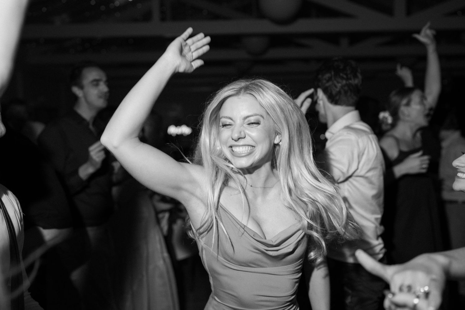 Black and white photo of wedding guest dancing at reception with hair in motion.