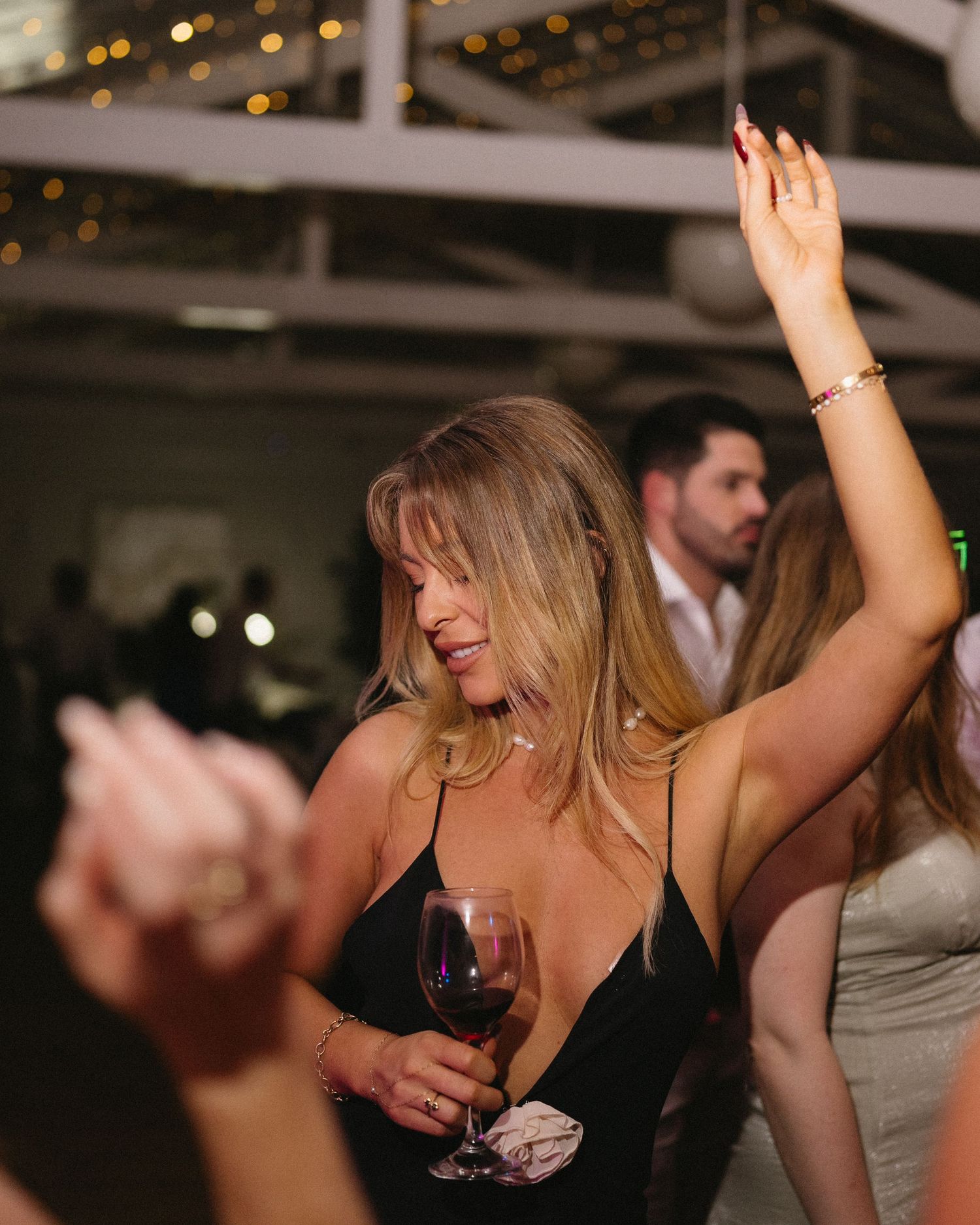 Wedding guest dancing with wine glass at evening reception party.