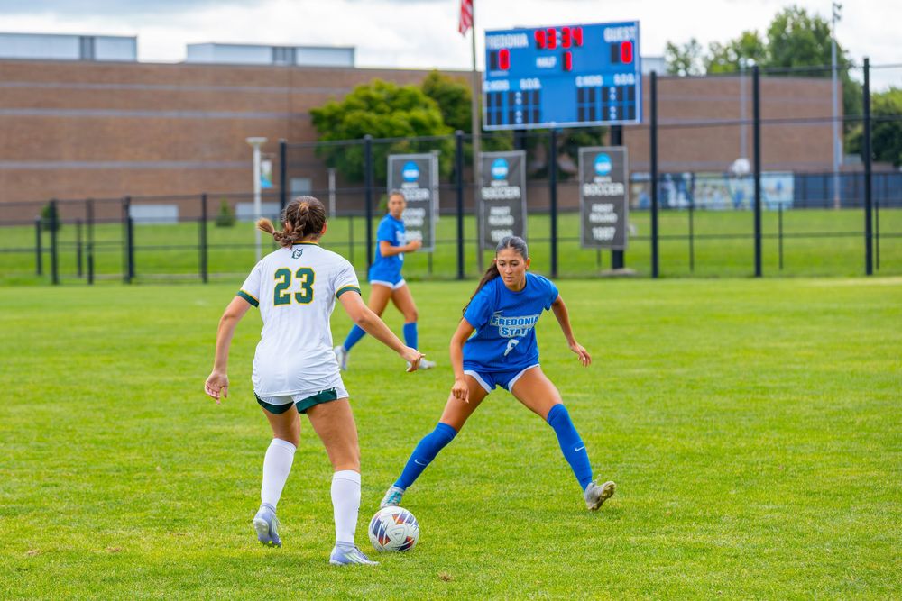 Soccer players compete for possession of the ball during an outdoor match on a grassy field.