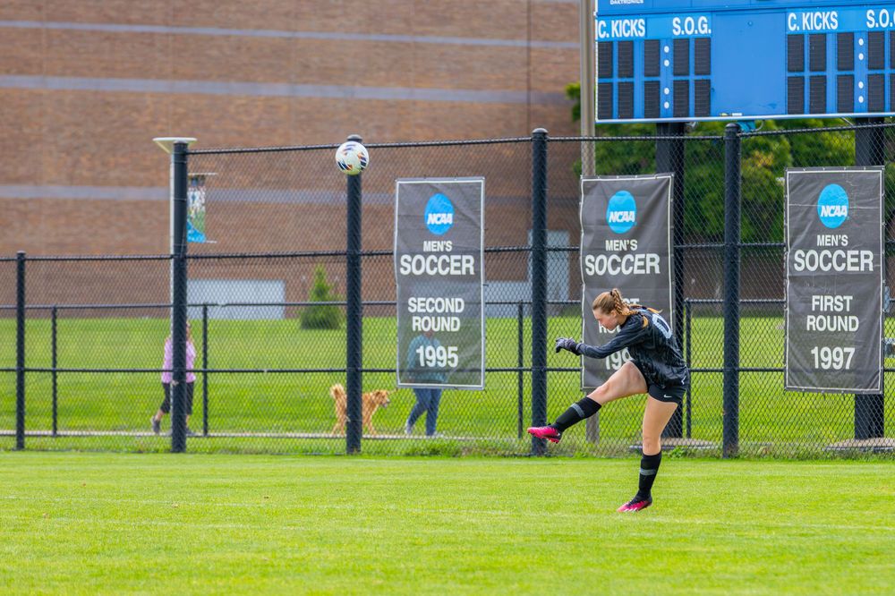 A long outdoor soccer field with banners and signage along the fence showing team accomplishments and years.