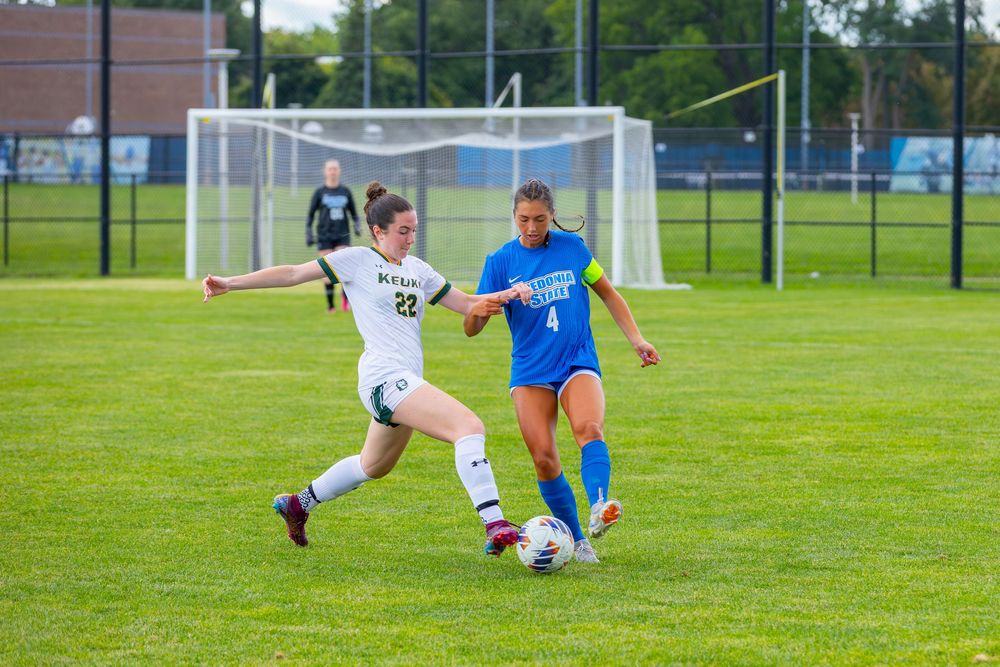 Soccer players compete for possession of the ball during an intense match on a green grass field.