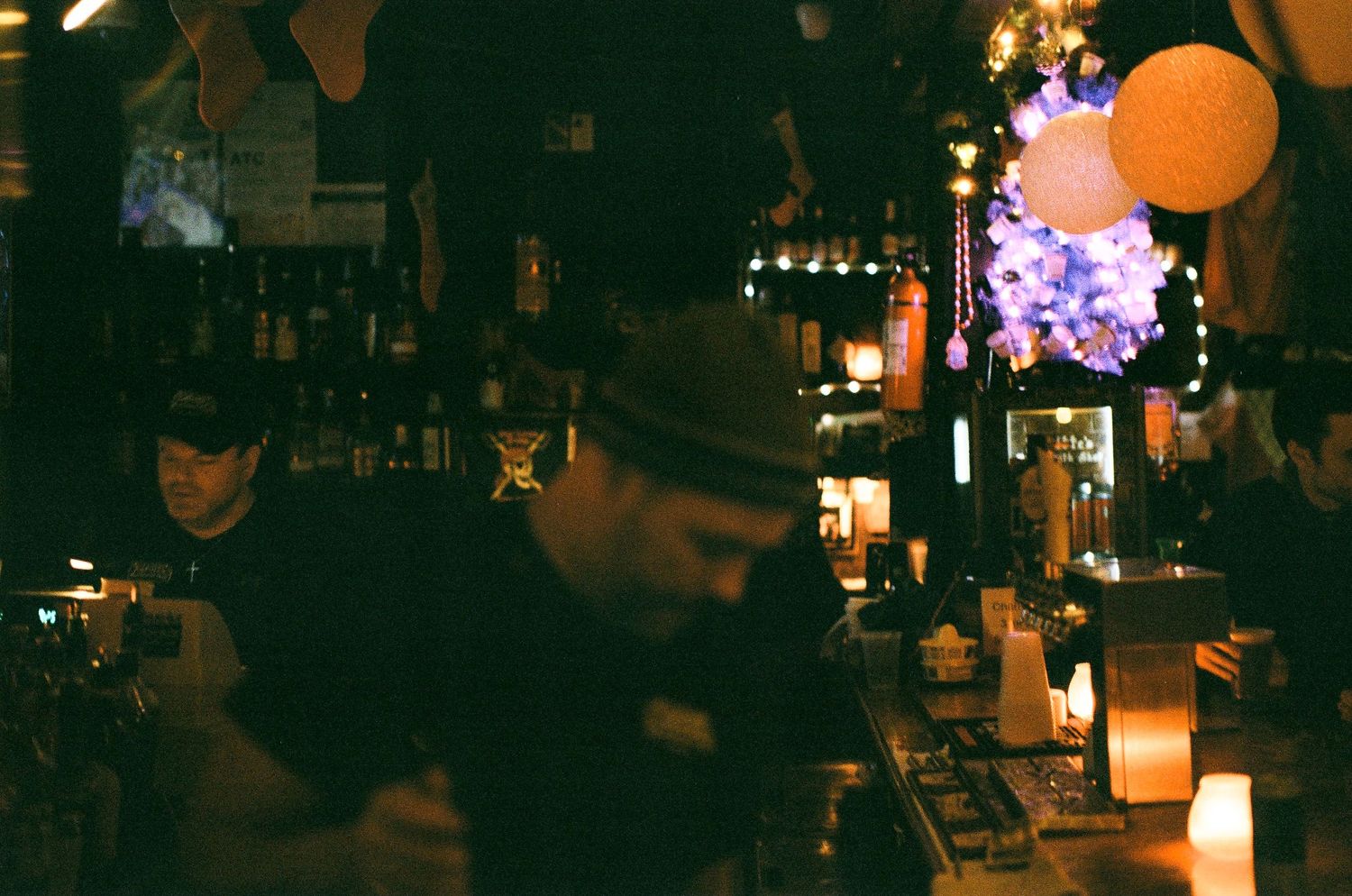 Atmospheric bar scene at night with warm lighting and patrons sitting along a dimly lit counter.