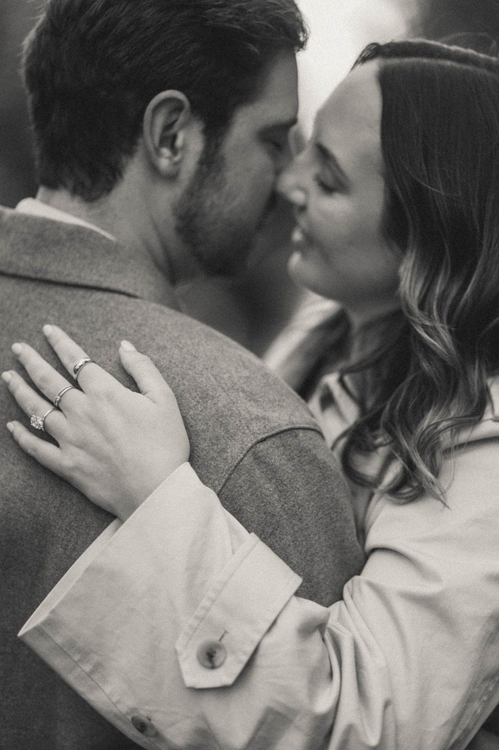 Intimate black and white portrait showing an engagement ring during a romantic embrace.