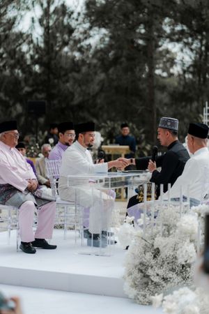 Religious officials conducting a traditional Islamic wedding ceremony on a decorated white stage.
