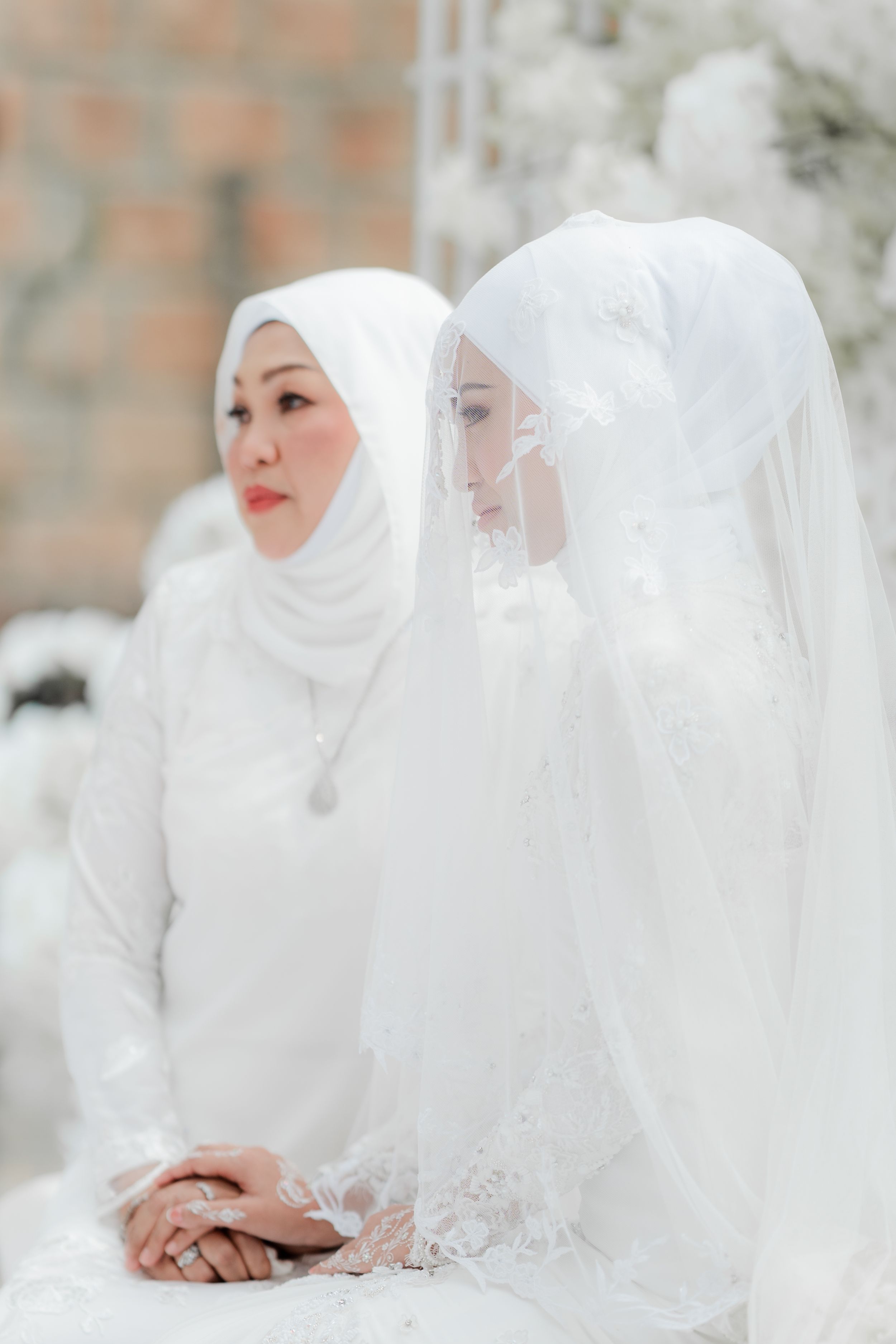 Two figures in white traditional Islamic attire seated together.