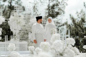 A traditional Islamic wedding ceremony with white decor and floral arrangements in an outdoor setting.