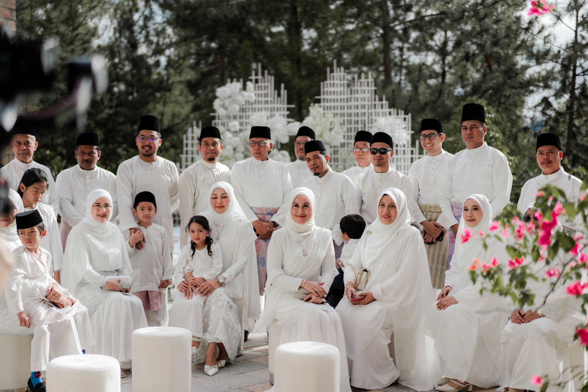 Wedding guests in coordinated white outfits seated in rows at outdoor ceremony.
