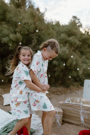 Two kids have a cuddle during a quick, fun, Christmas mini photography session on the beach in Wickham, WA