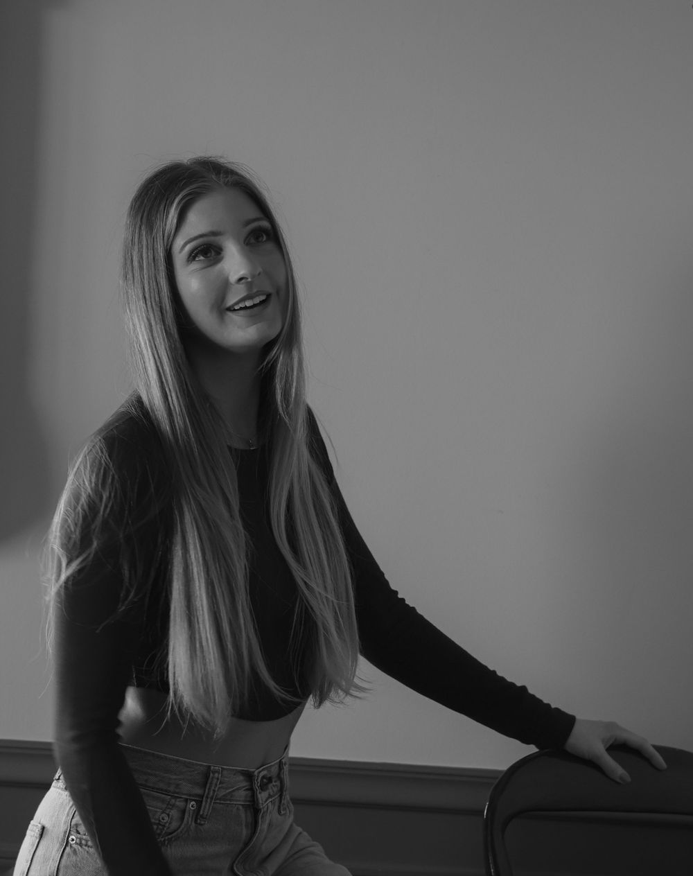 Black and white portrait style indoor photoshoot against grey wainscoting.