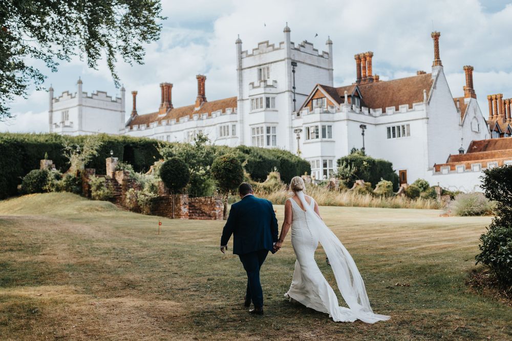 Bride and groom walking on castle lawn – wedding photography by Luis Gomes in Hertfordshire