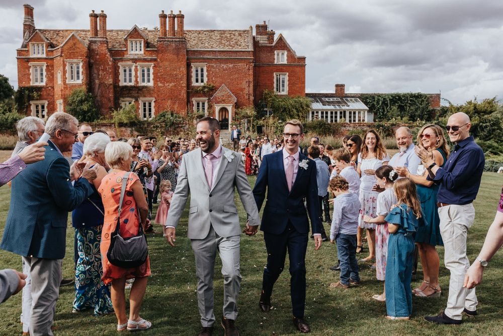 Wedding guests gathered outside red-brick manor house – wedding photographer Luis Gomes in Hertfordshire