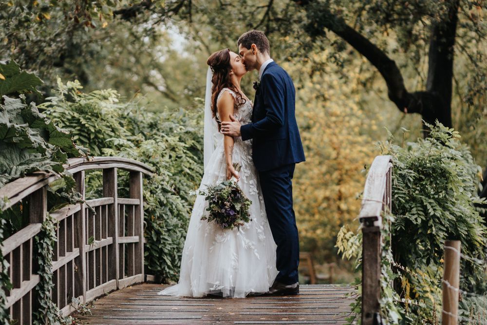 Groom holding bride on stone steps near river – wedding photography by Luis Gomes in Hertfordshire