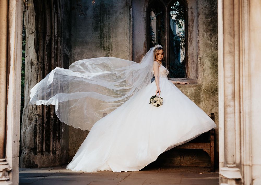Bride walking with flowing veil outside historic church – wedding photography by Luis Gomes in London
