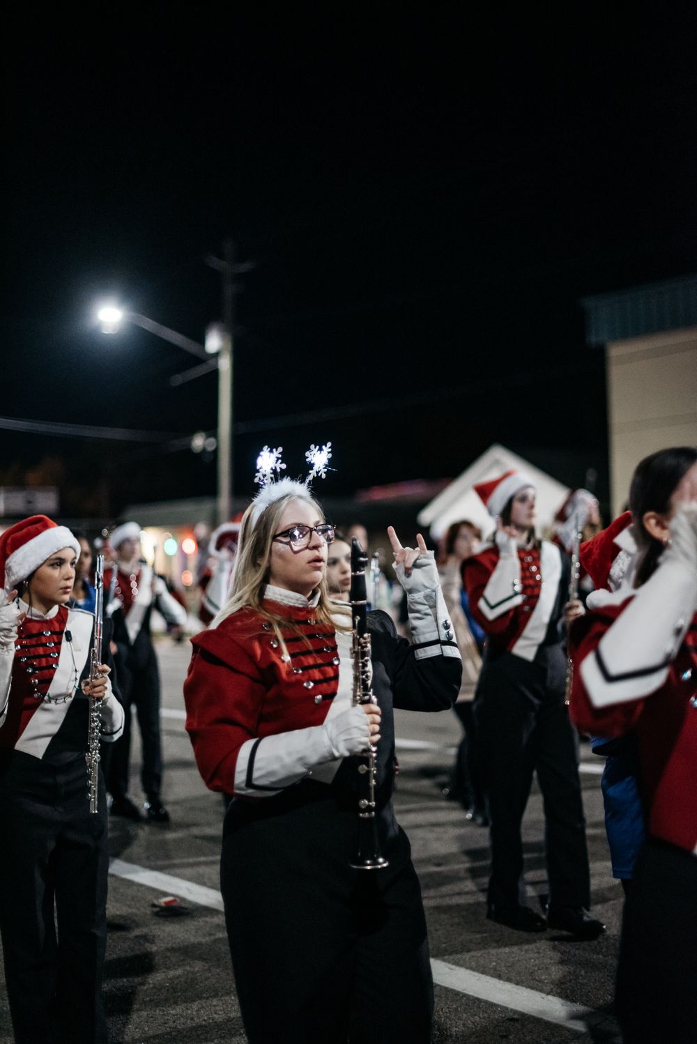 Band members perform in red and black uniforms during a nighttime marching formation.