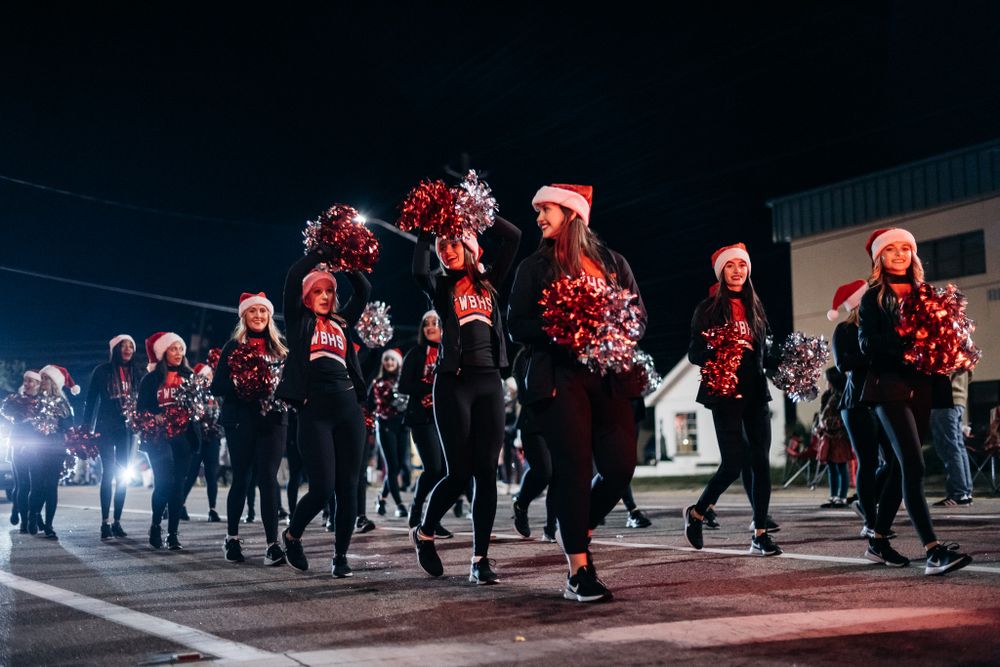 Dance team in red uniforms performs routine during nighttime street parade.