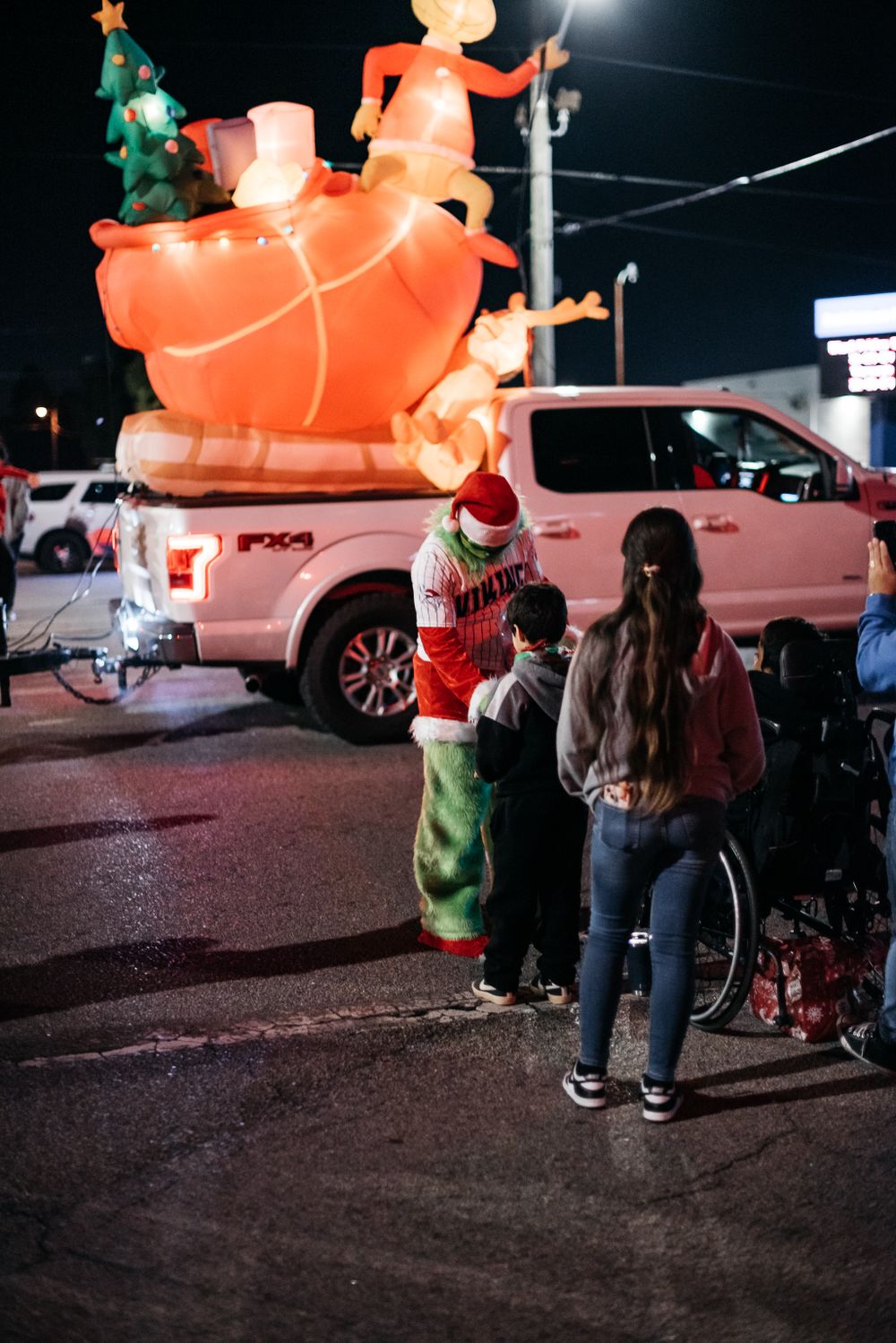 Children gather around giant inflatable pumpkin decoration at nighttime event.