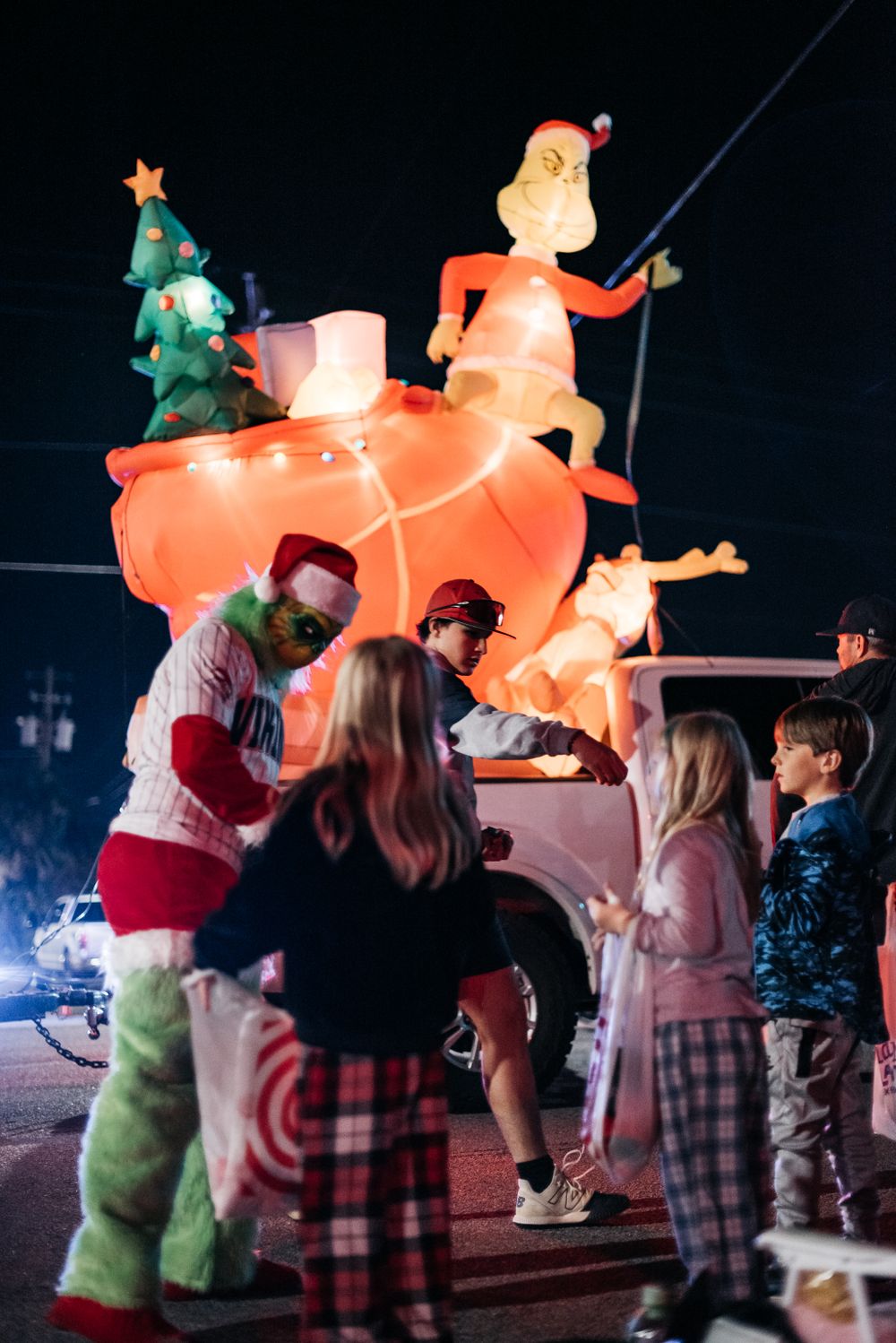 A large illuminated Santa Claus decoration glows orange against the night sky while people gather below.