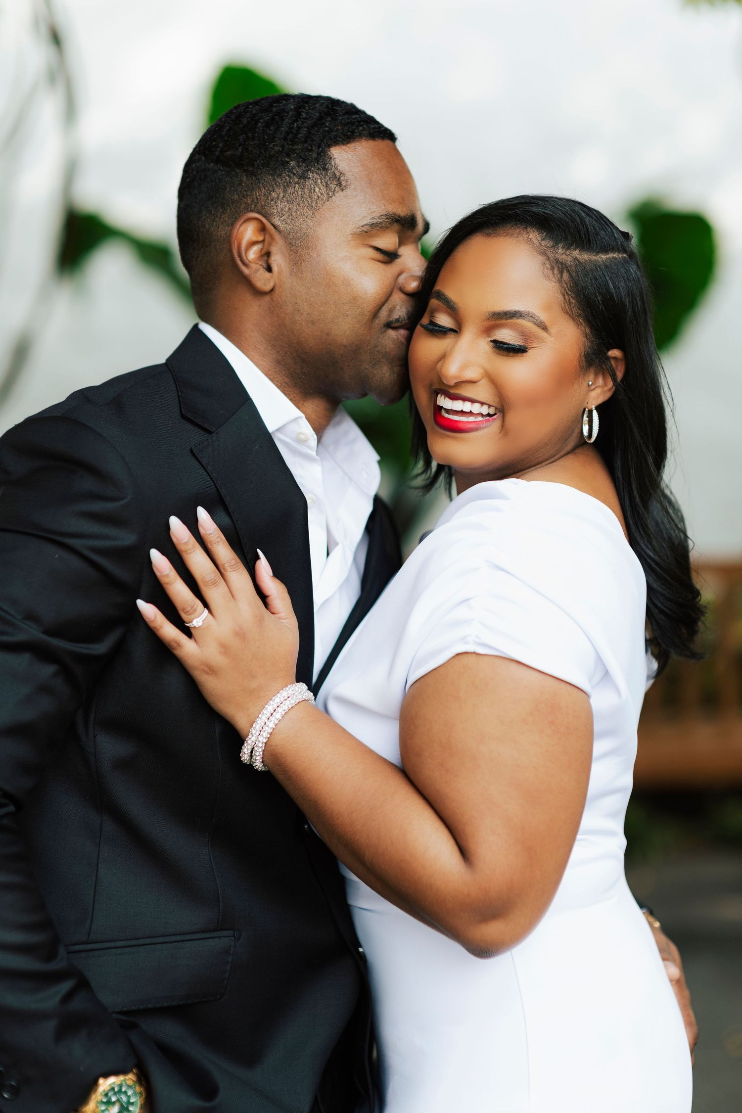 Engaged couple sharing a laugh under scenic garden arches