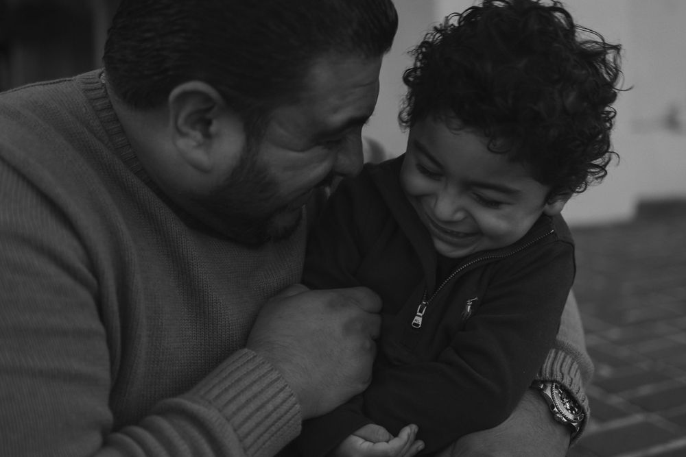 A black and white candid portrait showing a tender moment between parent and child in casual attire.