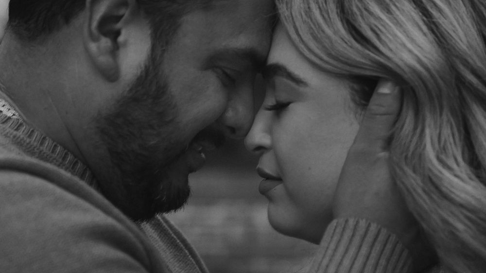 Black and white intimate portrait of a couple sharing a tender romantic moment.