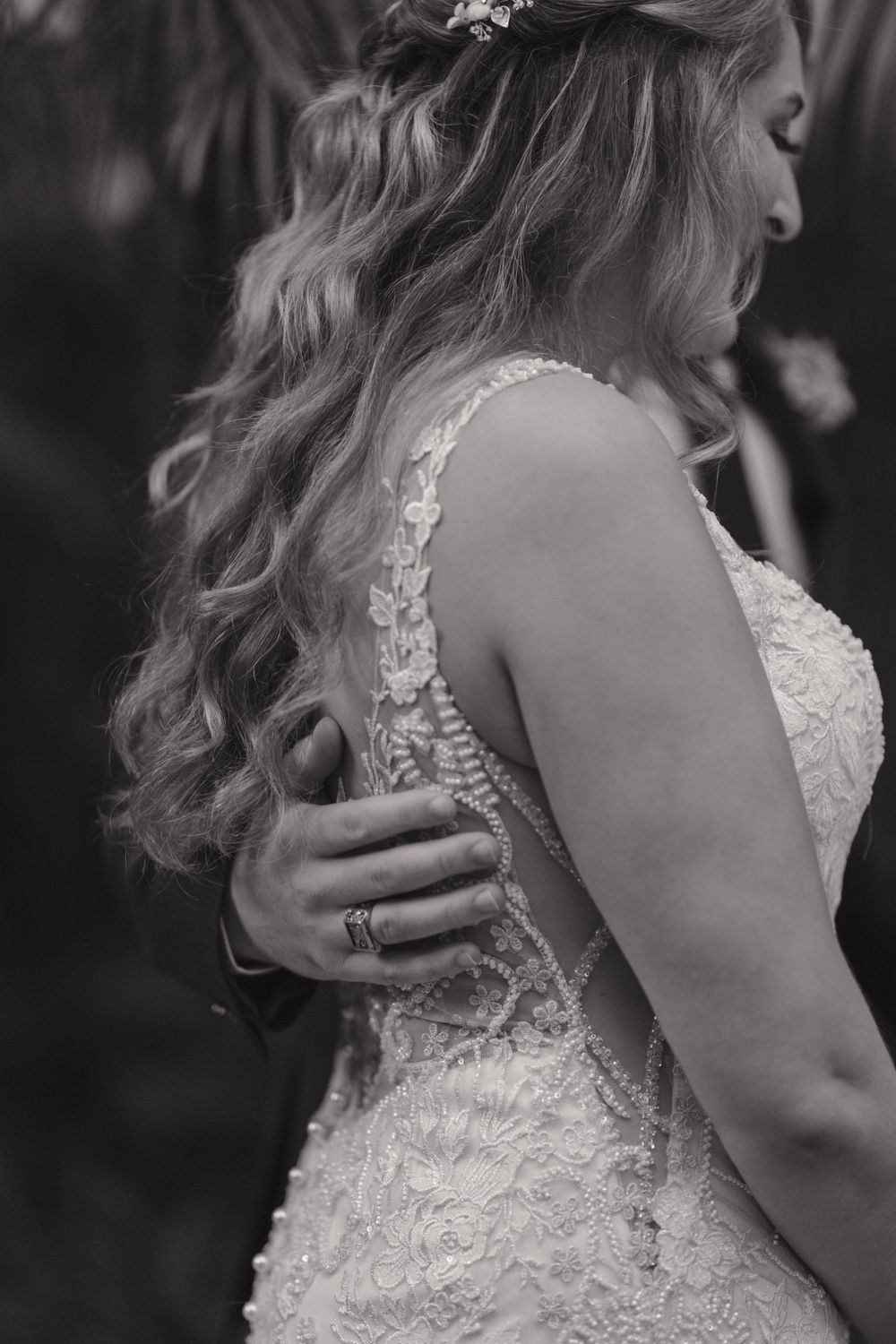 Detail shot of a bride in a lace wedding dress with flowing wavy hair styled for her special day.