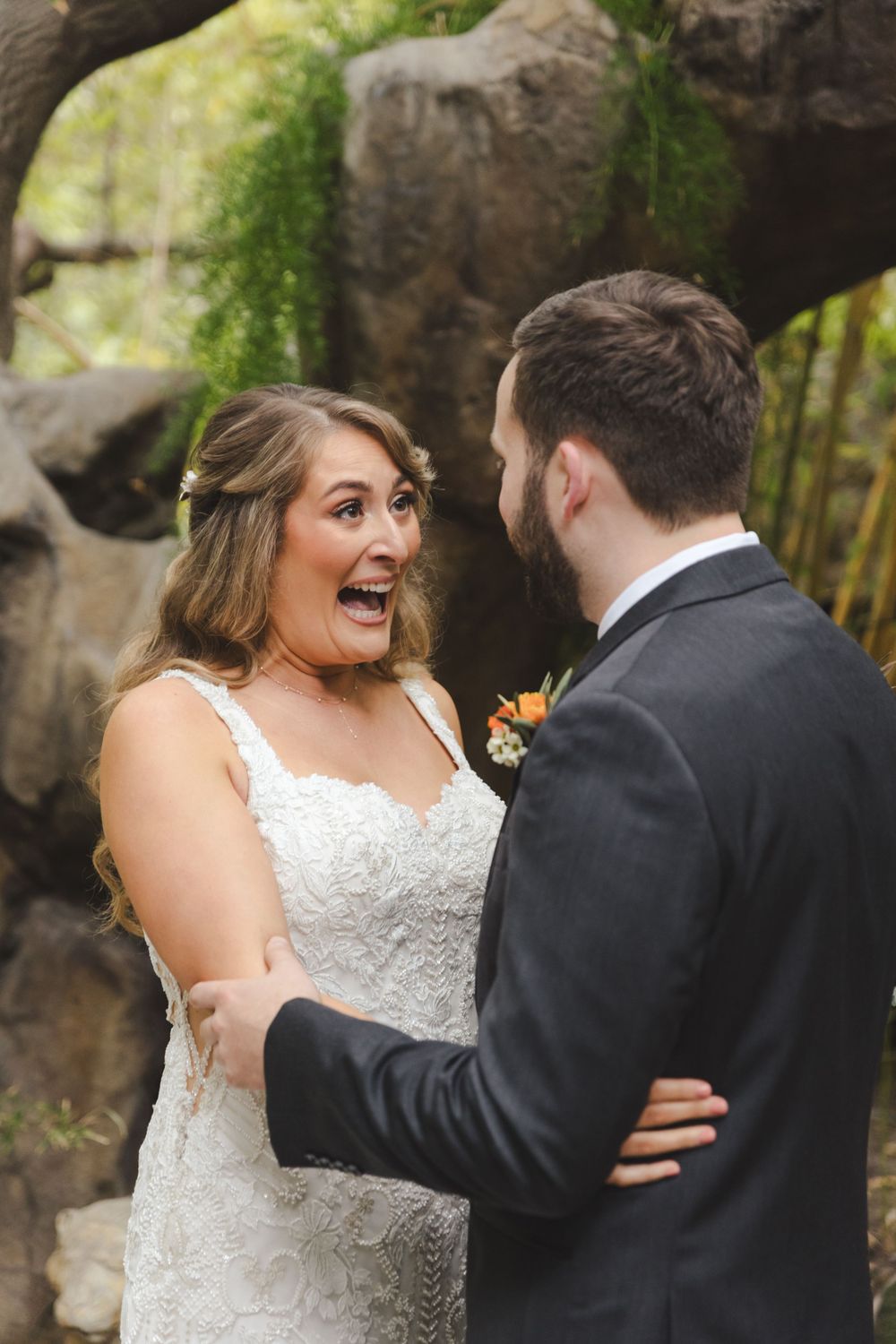 A candid moment between newlyweds during their outdoor wedding ceremony near a rock formation.