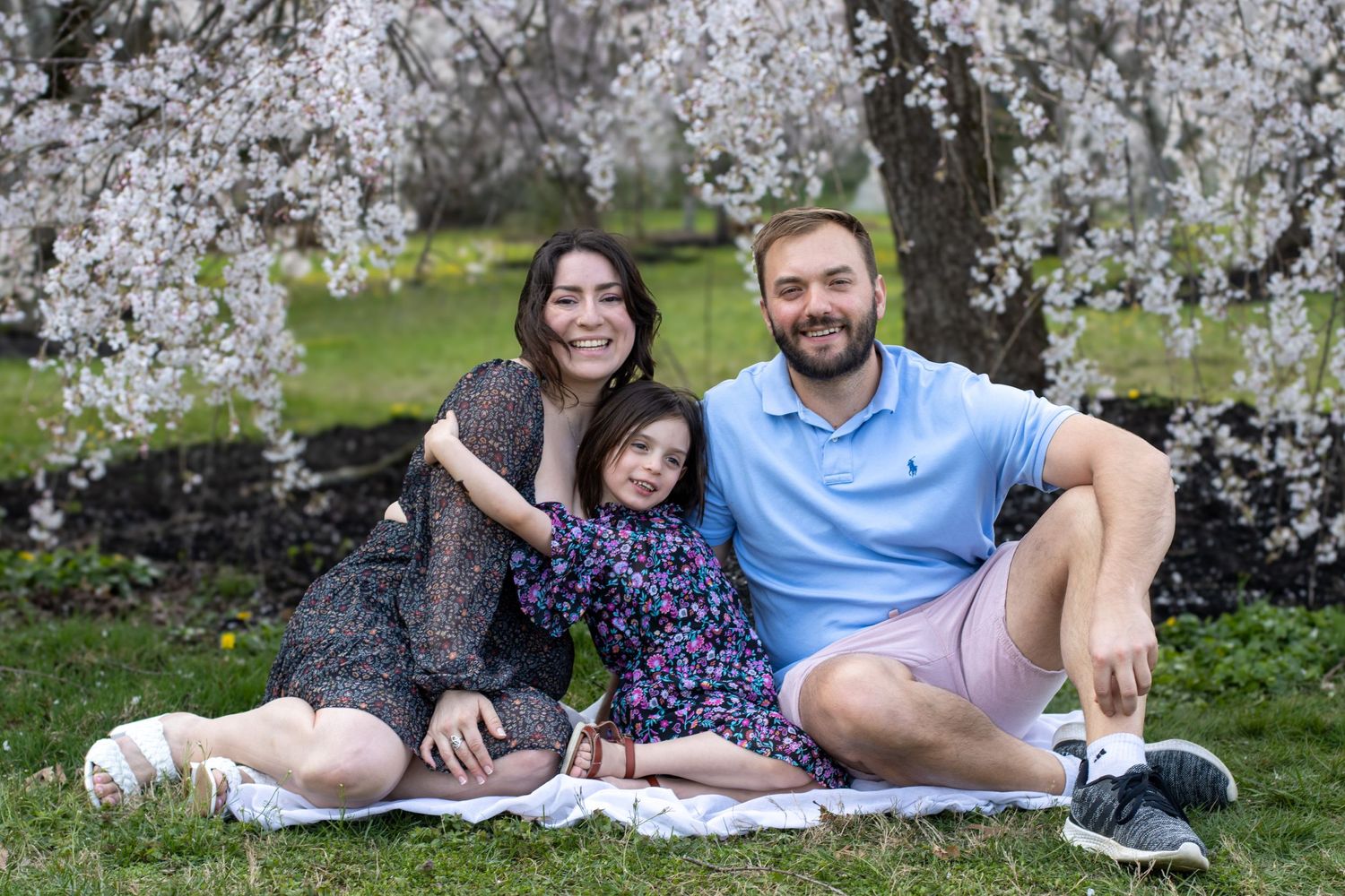 Family enjoying cherry blossom season at Ault Park, Cincinnati, surrounded by beautiful pink blooms and capturing joyful moments together.