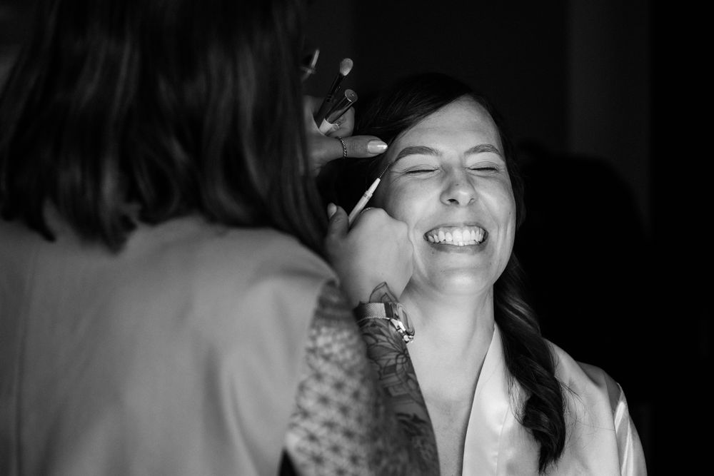 A candid black and white photograph captures a cheerful moment with eye closed and a bright laugh.