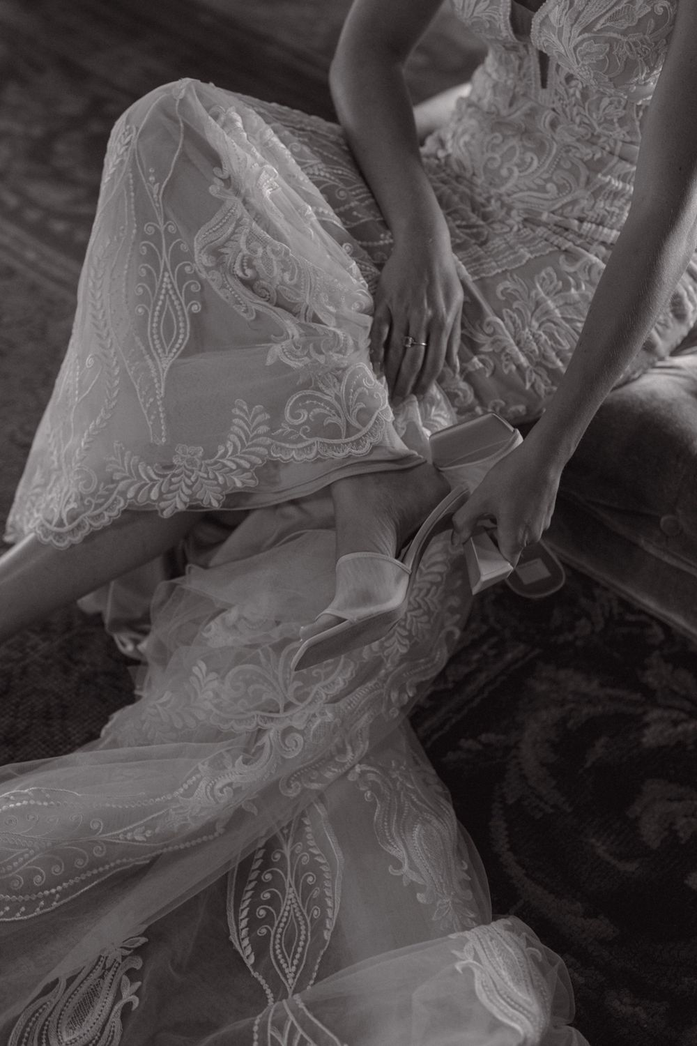 Close-up of an intricate white lace wedding dress with delicate floral embroidery patterns.