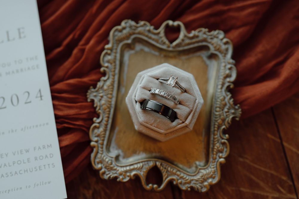 Wedding bands displayed in an ornate vintage frame with heart details on red velvet background.