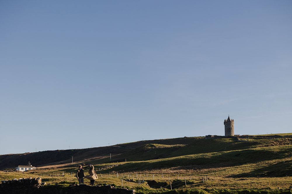couple is dancing at the sunset with Doonagore castle in the background